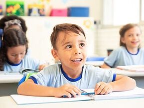Smiling boy sitting at desk in school classroom
